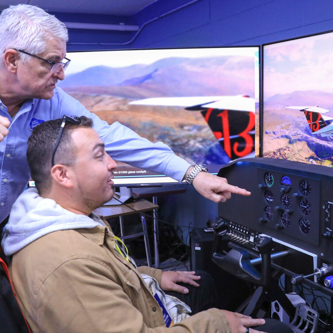 An alumni member receives instruction on our new flight simulator!